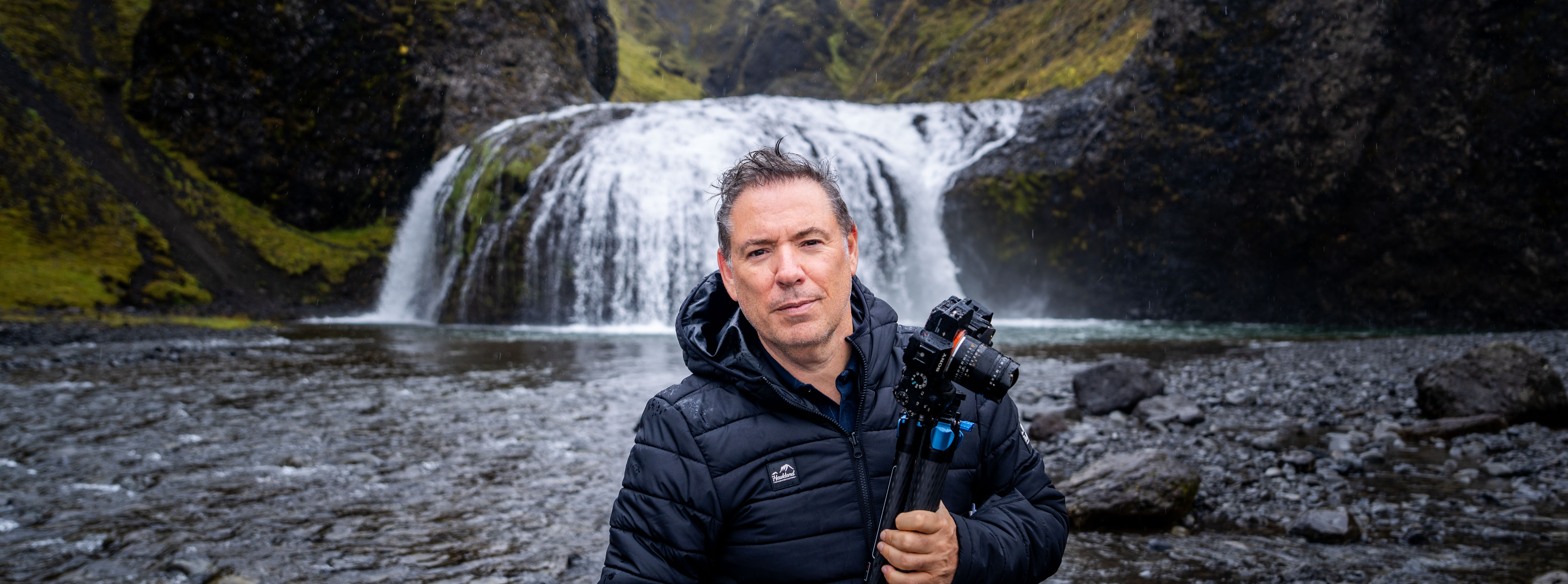 Serge Ramelli holding his camera beside a waterfall